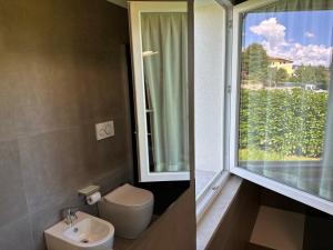 a bathroom with a toilet and a sink and a window at Hotel Riviera in Magnano in Riviera