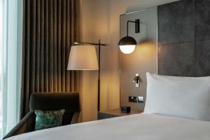 a bedroom with a bed and a lamp and a chair at Hilton Aberdeen TECA in Aberdeen