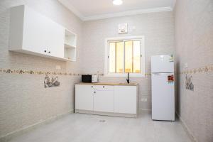 a kitchen with a white refrigerator and a window at Luxury & Charming Big Apartments in Mudhainib in AR Rummanah
