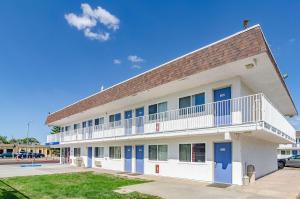 a large white building with blue doors and a parking lot at Motel 6 Cheyenne in Cheyenne