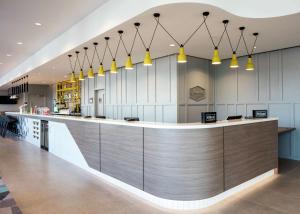 a lobby with a counter with yellow pendant lights at Hampton By Hilton Belfast City Centre in Belfast