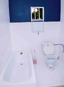 a white bathroom with a toilet and a window at Maisondulac7 in Rubavu