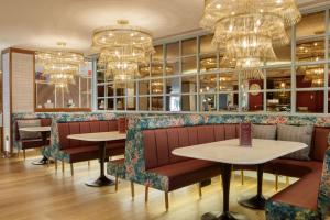 a restaurant with two tables and chairs and chandeliers at DoubleTree by Hilton Bath in Bath