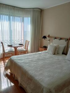 Un dormitorio con una cama grande y una mesa con sillas. en MZA Departamentos en Mendoza