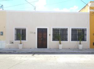 um edifício branco com dois vasos de plantas e uma porta em La Casa del Jaguar em Mérida