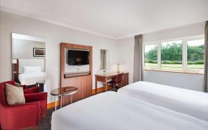 a hotel room with two beds and a red chair at DoubleTree by Hilton Coventry in Coventry +35 photos