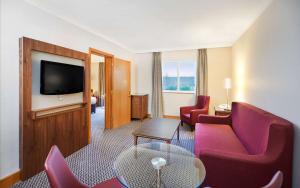 a hotel room with red chairs and a flat screen tv at DoubleTree by Hilton Coventry in Coventry