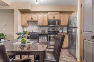 a kitchen with a table and chairs and a refrigerator at Spacious King Bed with Pool & Hot Tubs in Canmore +22 photos