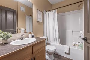 a bathroom with a sink and a toilet and a shower at Spacious King Bed with Pool & Hot Tubs in Canmore