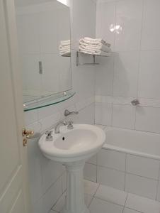 y baño blanco con lavabo y ducha. en MZA Departamentos en Mendoza