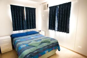 a bedroom with a bed and two black curtains at Tasman Holiday Parks - Kalbarri in Kalbarri