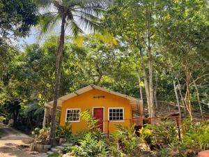 una pequeña casa amarilla en medio de árboles en La Casablanca Tayrona House en Calabazo