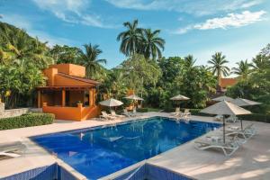 a pool at a resort with chairs and umbrellas at Hotel Ixzi Plus in Ixtapa