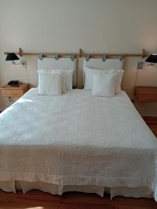 1 cama grande con sábanas y almohadas blancas en MZA Departamentos en Mendoza