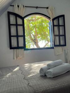a bedroom with a window with towels on a bed at Pousada 2 Baioco in Paty do Alferes