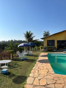 a pool with a table and chairs and an umbrella at Pousada 2 Baioco in Paty do Alferes
