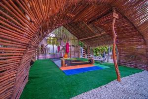 un padiglione in vimini con tavolo e parco giochi di SelvaLuz Tulum Resort & Spa a Tulum