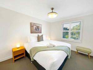 a bedroom with a large white bed and a window at Villa AlaBet in Pokolbin +11 photos