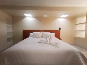 łóżko z dwoma łabędzie wykonanymi z ręczników w obiekcie ROYALS RESORT w mieście Huaraz