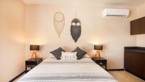 um quarto com uma cama e duas lâmpadas na parede em Ophelia Tulum em Tulum