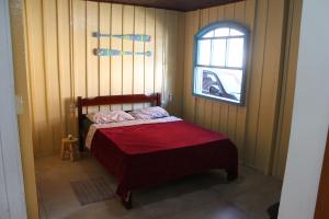a small bedroom with a bed with a window at Casa das Ondas in Itapoa