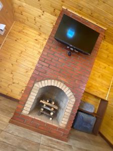 a brick fireplace with a tv on top of it at Chalés Canto da Serra in Monte Verde
