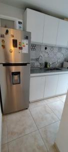 une cuisine avec un réfrigérateur en acier inoxydable et des armoires blanches dans l'établissement Duplex cómodo y elegante zona alta de Mendoza, à El Challao