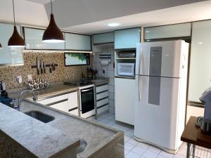 a kitchen with a white refrigerator and a sink at Maravilhosa casa Ponta de Serrambi in Porto De Galinhas