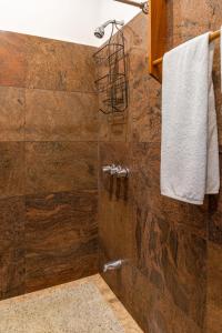 uma casa de banho com um chuveiro e uma parede de pedra em Mot Mot Vacation em Sámara