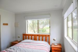 a bedroom with a bed and two windows at The Big Bell Farm in Kangaroo Valley