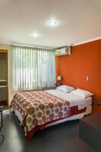 una camera con un grande letto con una parete arancione di Hotel Stella Talca a Talca