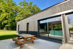 einem Picknicktisch aus Holz auf einer Terrasse neben einem Gebäude in der Unterkunft Le Cottage proche du Golf in Panazol