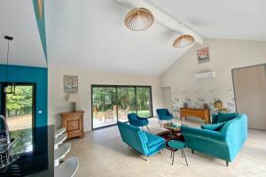 uma sala de estar com um sofá azul e cadeiras em Le Cottage proche du Golf em Panazol