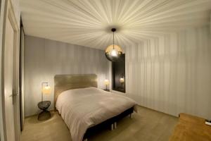 um quarto com uma cama grande e um lustre em Le Cottage proche du Golf em Panazol
