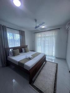 a bedroom with a large bed in a room with windows at Grey Pearl Apartments Where Raha is Also Our Priority in Malindi