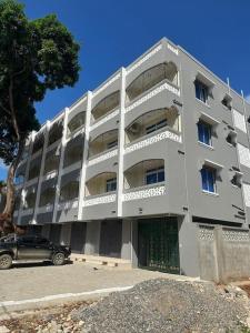 un bâtiment avec une voiture garée devant lui dans l'établissement Grey Pearl Apartments Where Raha is Also Our Priority, à Malindi