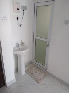 La salle de bains blanche est pourvue d'une douche et d'un lavabo. dans l'établissement Grey Pearl Apartments Where Raha is Also Our Priority, à Malindi