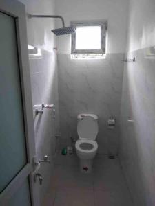 Elle comprend une petite salle de bains pourvue de toilettes et d'une fenêtre. dans l'établissement Grey Pearl Apartments Where Raha is Also Our Priority, à Malindi