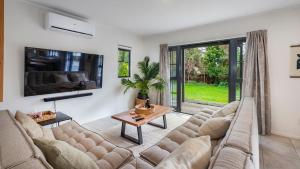 a living room with a couch and a table at Matakana Village Central - Modern Holiday Home in Matakana
