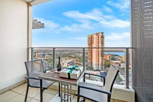 a balcony with a table and chairs and a view of a city at Metropolis Mirage - A Poolside CBD Studio in Darwin
