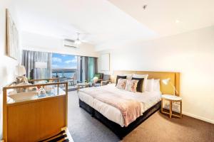 a bedroom with a bed and a desk with a view at Metropolis Mirage - A Poolside CBD Studio in Darwin +12 photos