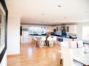 a kitchen and dining room with white cabinets and white chairs at 2 Princes Cottages in Plymouth