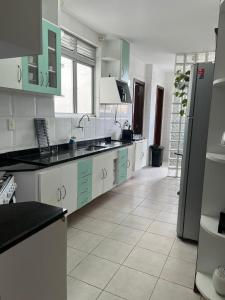 una cocina con armarios blancos y verdes y suelo de baldosa. en Cobertura com piscina em Cabo Frio, en Cabo Frío