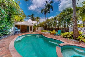 a swimming pool in a yard with palm trees at The Wee Cottage in Anna Maria