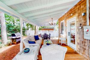 a covered porch with wicker chairs and a table at Come About Cottage in Wareham