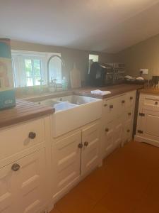 a kitchen with white cabinets and a sink at Little half point in Welton