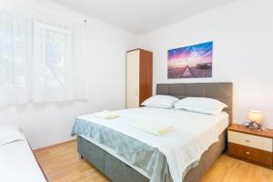 een witte slaapkamer met een groot bed. bij Apartments with a parking space Cove Smrceva, Brac - 20193 in Milna