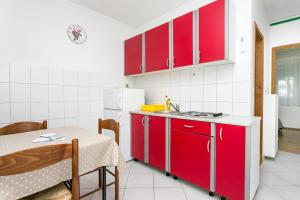 een keuken met rode kasten en een tafel en een tafel en een tafel bij Apartments with a parking space Cove Smrceva, Brac - 20193 in Milna