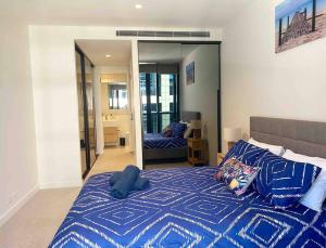 een slaapkamer met een bed met een blauw dekbed en een spiegel bij So Unique! Collins Street Vibe 2B2B in Melbourne