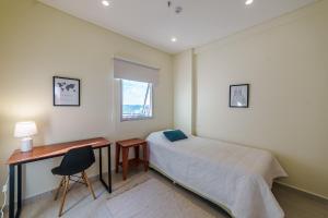 a bedroom with a bed and a desk and a window at Villa morra, a pasos de los shoppings! in Asuncion